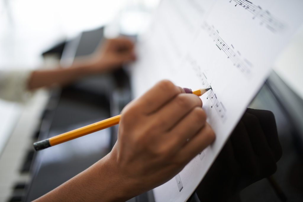 person writing on the music sheet
